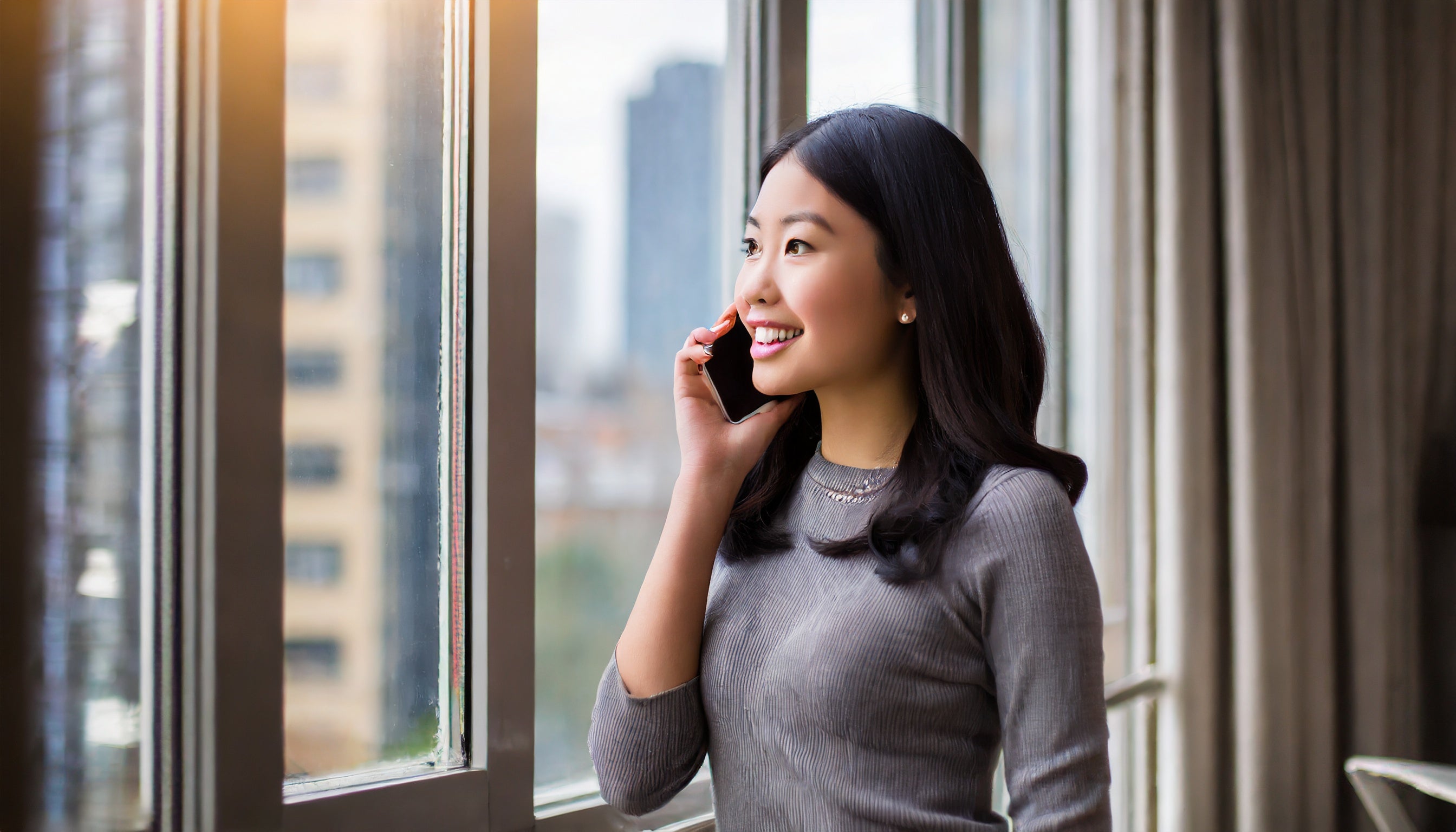 Photo of woman standing by window and talking on the phone