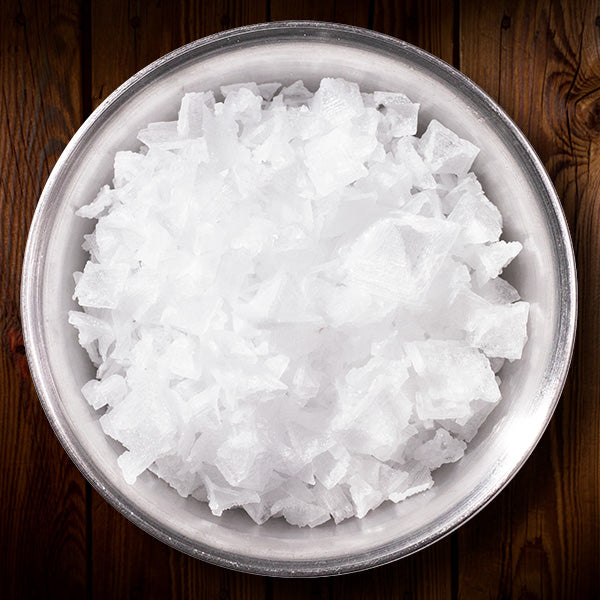 Natural pyramid flake salt in a circular metal container